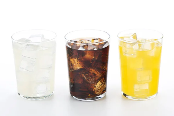 Kola, portakal ve limon dolu bardaklar. Beyaz arka planda üç ferahlatıcı içecek..