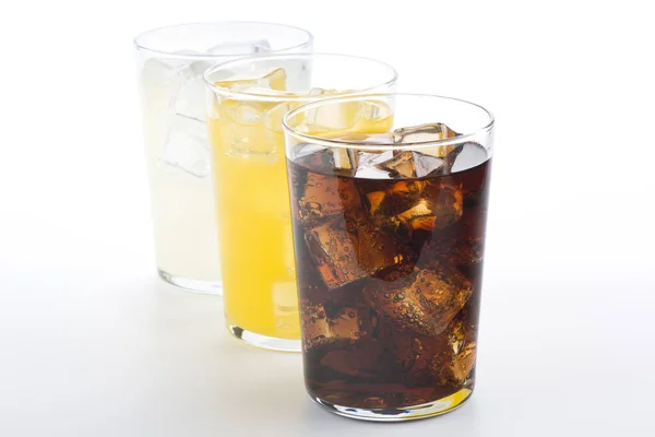 Kola, portakal ve limon dolu bardaklar. Beyaz arka planda üç ferahlatıcı içecek..