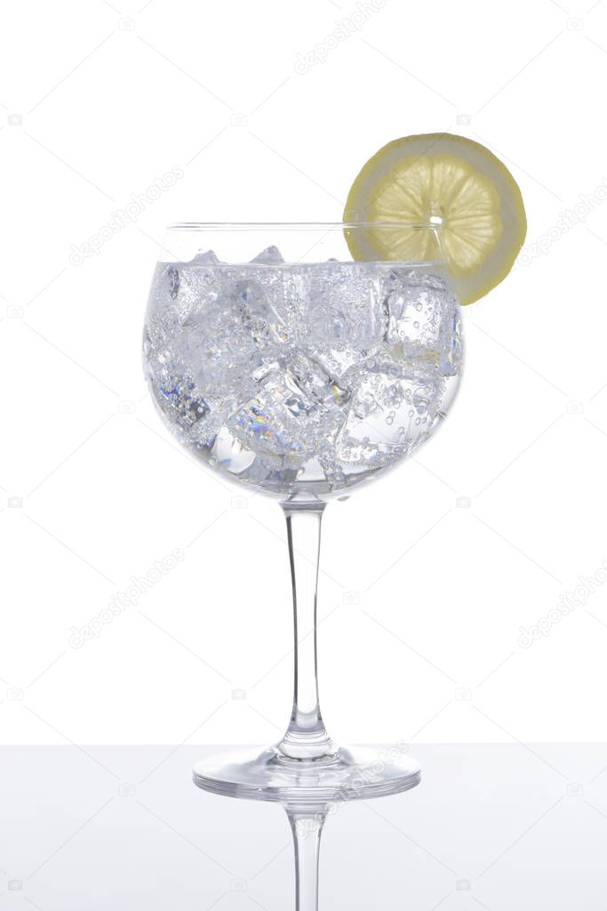 Glass of gin and tonic with a slice of lemon on white background