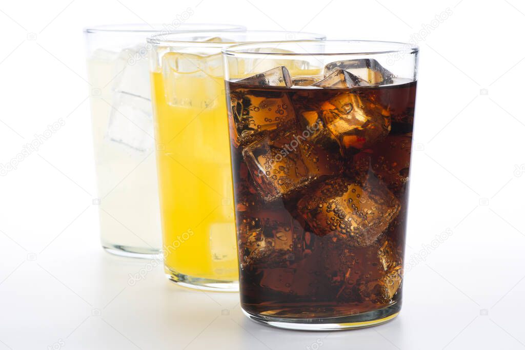 Glasses with soft drinks of cola, orange and lemon. Three refreshing drinks on white background.