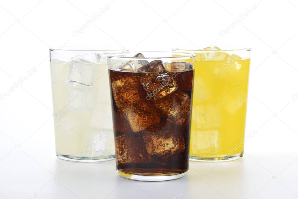 Glasses with soft drinks of cola, orange and lemon. Three refreshing drinks on white background.