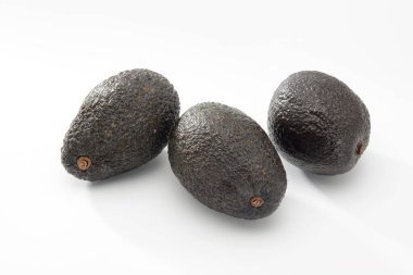 Beyaz zemin üzerinde üç avokado