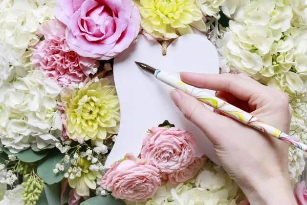 Woman writing greetings on white angel's wings. Romantic flower — Stock Photo, Image