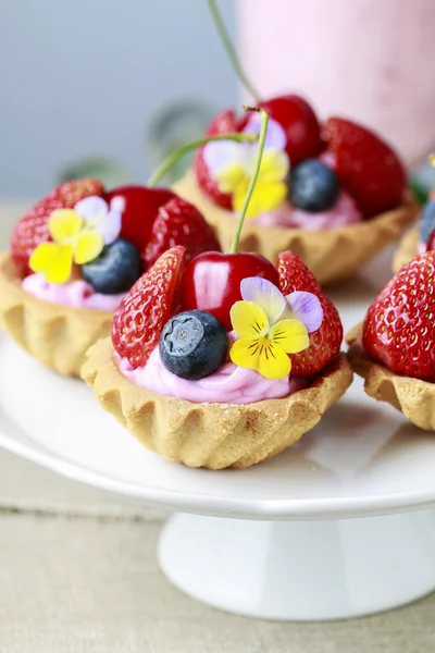 Pasteles con frutas frescas y flores comestibles . —  Fotos de Stock