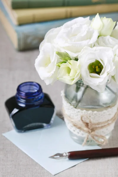 Bouquet of white eustoma flowers, bottle of ink and vintage pen.