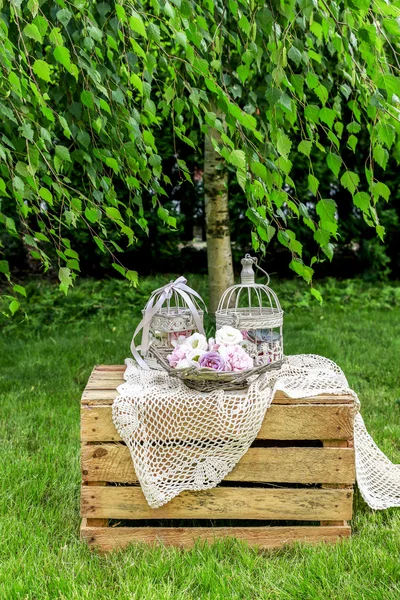 Garden party decorations: basket of flowers and vintage bird cag — Stock Photo, Image