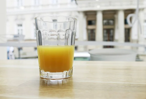 Half full or half empty glass of orange juice by the window.