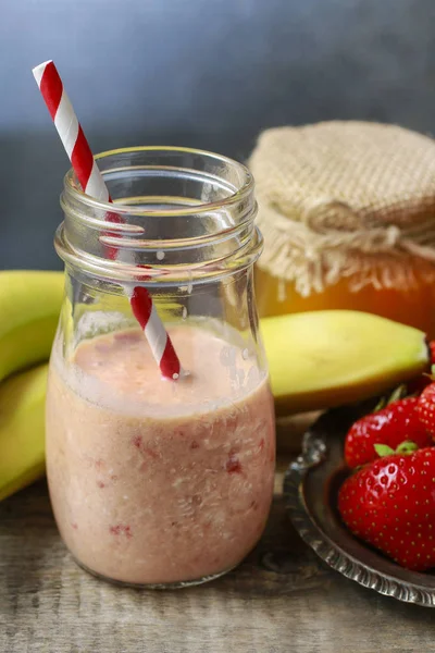 Śniadanie: butelka smoothie truskawek, bananów i miodu. — Zdjęcie stockowe