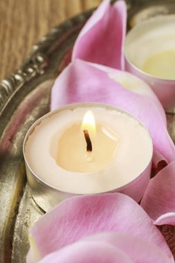Pembe gül yaprakları arasında küçük mumlar