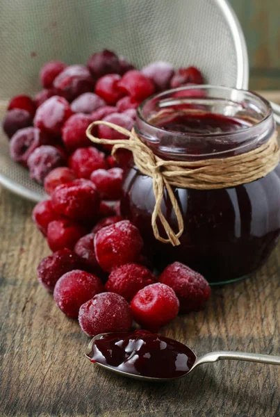 Spoon of jam and frozen cherries — Stock Photo, Image
