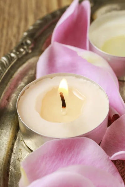 Крошечные свечи среди розовых лепестков роз — стоковое фото
