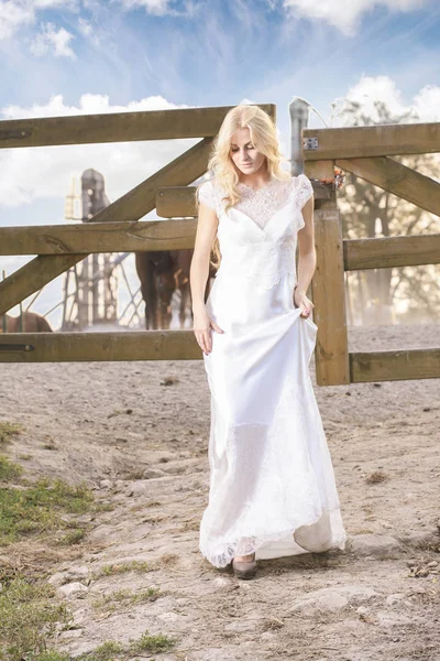 Young bride, beautiful blonde, at horse ranch