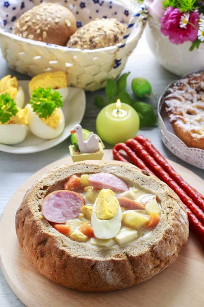 The sour rye soup inside loaf of bread. Easter breakfast table. — Stock Photo, Image