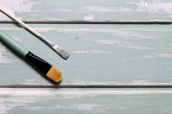 Two brushes and mint chalk paint on wooden surface — Stock Photo, Image