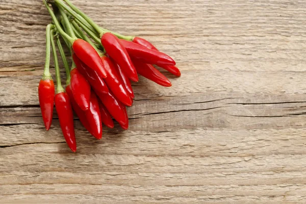Rode hete chili pepers op oude houten tafel — Stockfoto