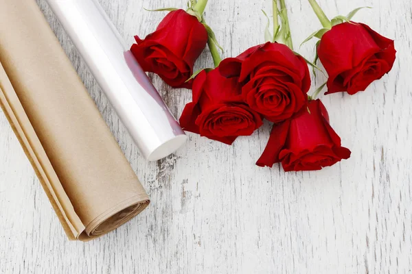 Paper or plastic stretch film as wrapping for red rose flowers.
