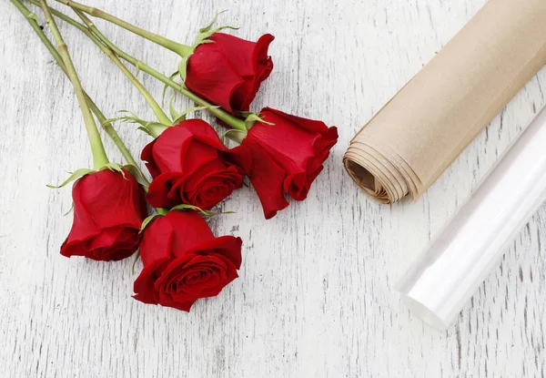 Papier oder Stretchfolie als Verpackung für rote Rosenblüten. — Stockfoto