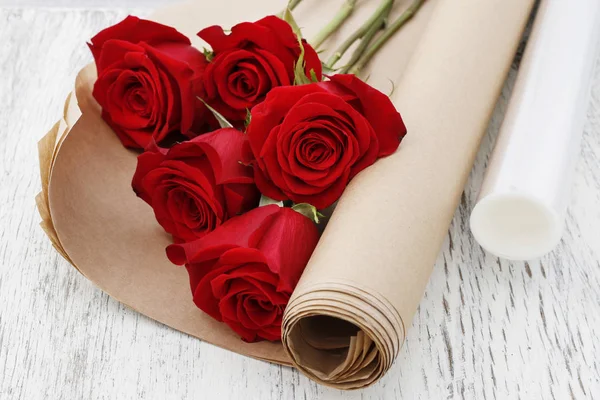 Filme de estiramento de papel ou plástico como embalagem para flores vermelhas de rosa . — Fotografia de Stock