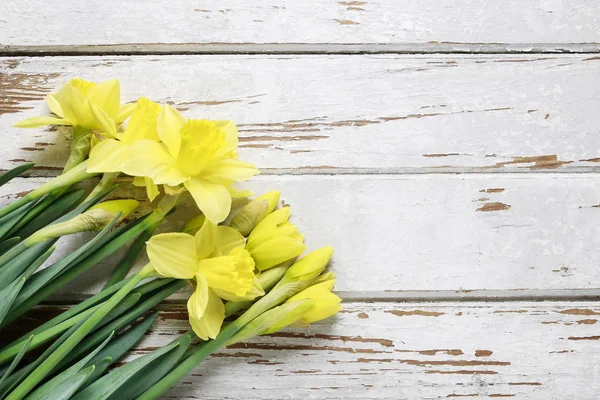 Hermosos narcisos amarillos sobre mesa de madera blanca . — Foto de Stock