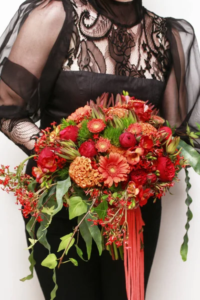 Diva after the concert holding huge bouquet of red and orange fl