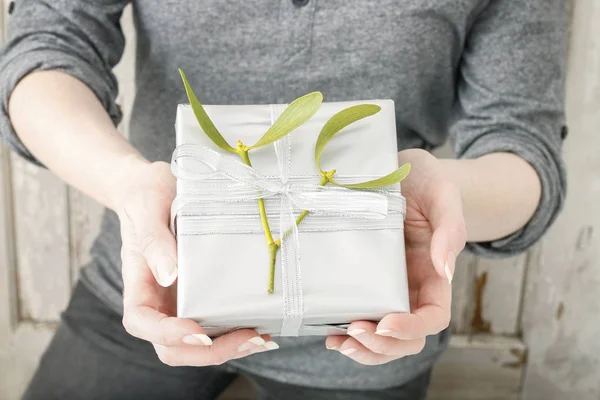 Femme tenant cadeau de Noël décoré avec brindille de gui . — Photo