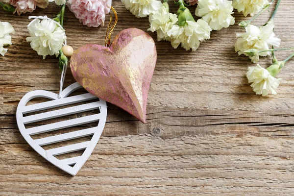 Corazones y flores de clavel sobre fondo de madera . —  Fotos de Stock