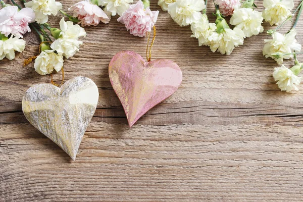Coeurs et fleurs d'oeillet sur fond en bois . — Photo