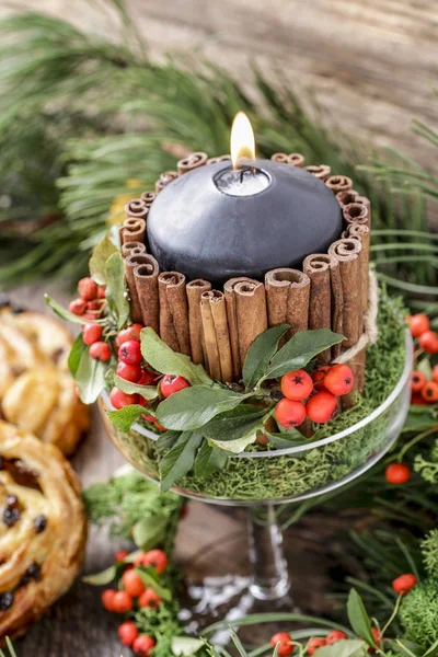 Candle decorated with cinnamon sticks and red berries (cotoneast — Stock Photo, Image