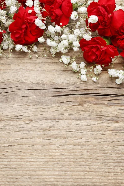 Red carnations and gypsophila paniculata on wooden background — Stock Photo, Image