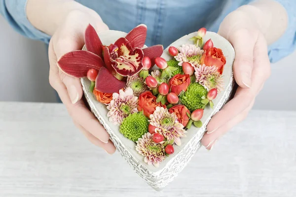 Kvinna som håller hjärta gjord av blommor. — Stockfoto