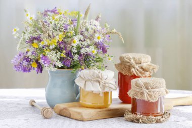 Ballı kavanozlar ve masada bir buket yabani çiçek..