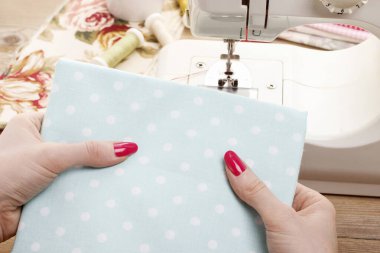 Kadın elinde benekli bir kumaş tutuyor.