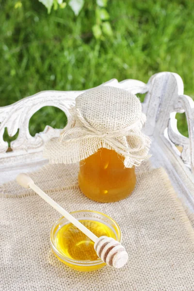 Jar of honey on wooden table in the garden. — Zdjęcie stockowe