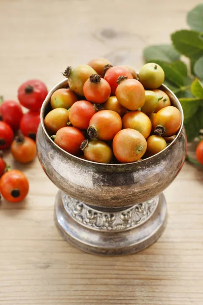 Vintage striped box of rose hip fruits on wooden table. — Stock Photo, Image