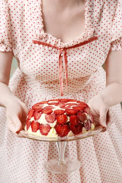 A woman in a white polka dot dress is holding a strawberry cake — Stock Photo, Image