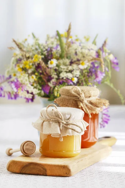 Burkar med honung och bukett vilda blommor på bordet. — Stockfoto