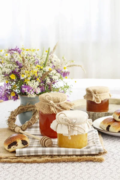 Vasi con miele e bouquet di fiori selvatici sul tavolo . — Foto Stock