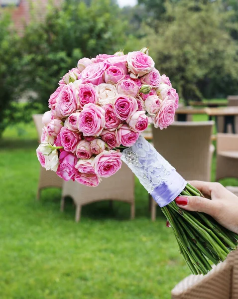 Женщина держит свадебный букет из крошечных розовых роз . — стоковое фото