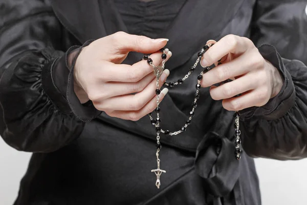 Witwe im schwarzen Kleid mit einem Rosenkranz in der Hand. — Stockfoto