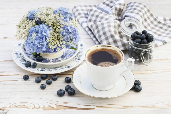 Чашка кофе и цветочные композиции с голубой гортензией — стоковое фото