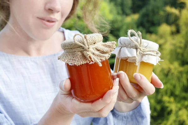 Woman holds glass jars with honey. — Stock Photo, Image