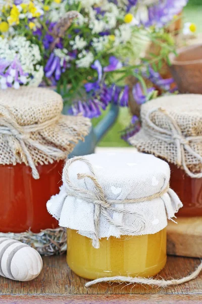 Vasi con miele e bouquet di fiori selvatici in giardino . — Foto Stock