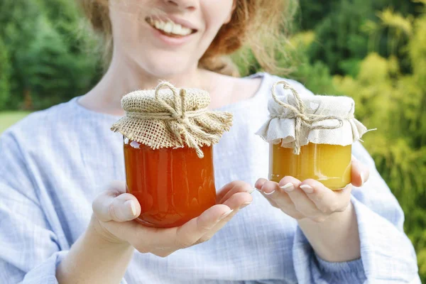 Woman holds glass jars with honey. — Stock Photo, Image