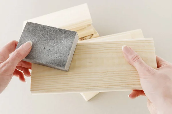 Kobieta używa papieru ściernego do renowacji drewnianej powierzchni. — Zdjęcie stockowe