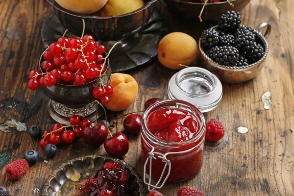 Jar of strawberry jam among summer and autumn fruits — Stock Photo, Image