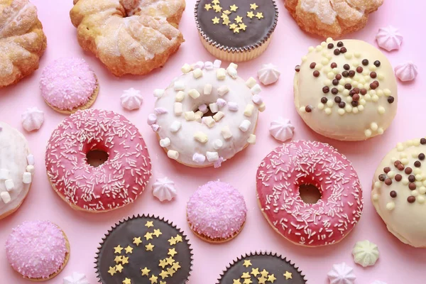 Verschillende soorten donuts en andere cakes op roze achtergrond. — Stockfoto