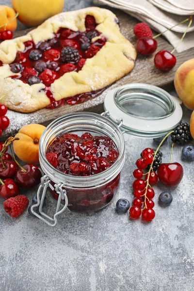 Jar of cherry jam among fresh fruits on grey stone background. — ストック写真