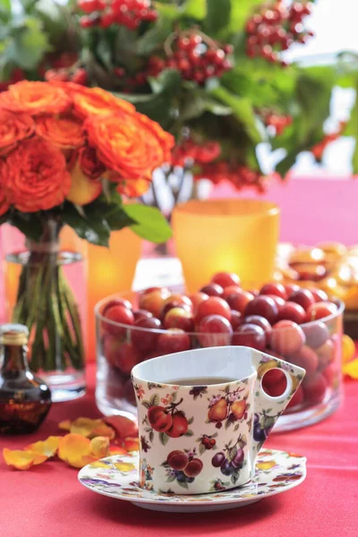 En kopp te på bordet. Höstdekorationer med rosenblommor — Stockfoto