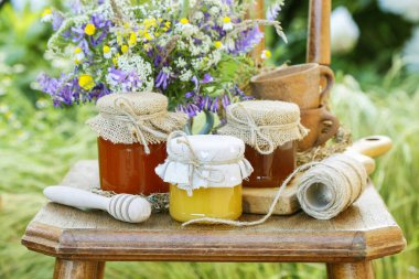 Ballı kavanozlar ve bahçede bir buket yabani çiçek. 