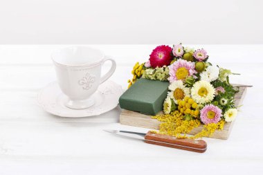 Kadın, yaz çiçekleriyle nasıl çiçek aranjmanı yapılacağını gösteriyor.